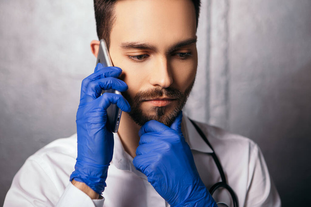 Człowiek mówiący trzymaj telefon nowoczesny gadżet pokazać kciuk w górę jak gest. Lekarz pielęgniarka ubrana w białą koszulę z niebieskim wirusowe jednorazowe rękawice maska twarzy stetoskop szyi. Przestrzeń kopiowania  - Zdjęcie, obraz