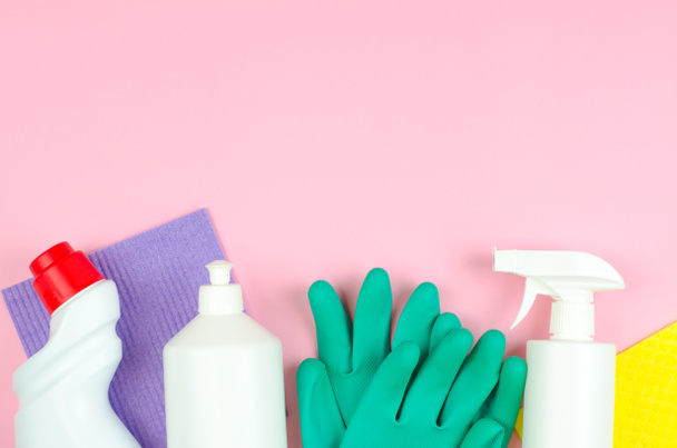 Cleaning products on a pink background. White bottles with detergents and cleaning products, sponges and gloves on a rose background with place for text. Cleaning tools company concept. - Photo, Image