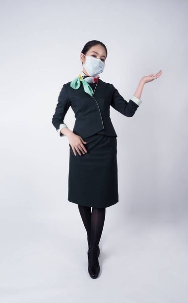 Équipage de cabine ou hôtesse de l'air avec masque facial dans Covid 19 pandémie. Les agents de bord portent un masque médical pour prévenir l'infection par le coronavirus. Nouveau mode de vie normal dans les affaires aériennes. Jolie hôtesse femme. - Photo, image