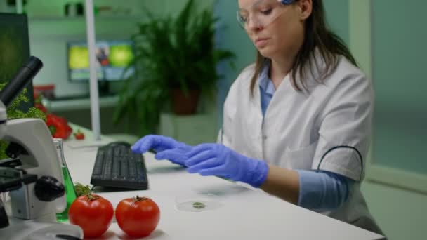 Bitkibilimci kadın elinde yaprak örneğiyle petri kabına bakıyor. - Video, Çekim