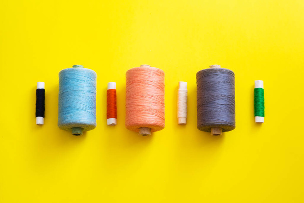 Reels with threads of different colors and sizes on a bright, colorful background. Flat lay - Photo, Image