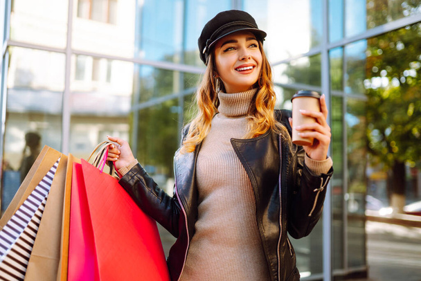 Beautiful woman after spring shopping drinking coffee walking around the city. Consumerism, black friday, sales, lifestyle concept. - Foto, imagen