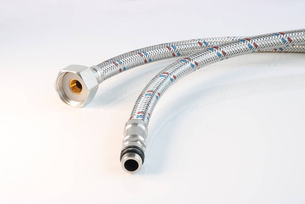 Flexible water line with connections on a light background. Plumbing accessories. - Photo, Image