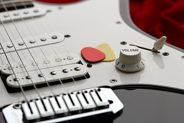 Elektrische gitaar close-up, rode achtergrond, niemand. Strijkmuziekinstrument, electro geluid, elektronische muziek, apparatuur voor podiumconcert - Foto, afbeelding