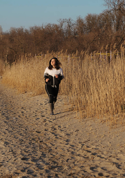 Corriendo hermosa joven en la playa. Concepto fitness. Mujer hace ejercicios al aire libre. - Foto, imagen