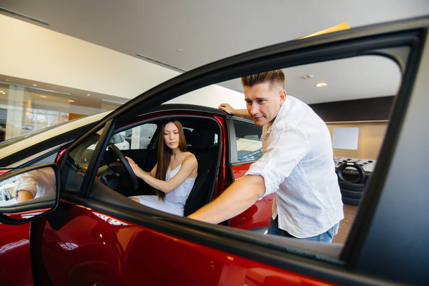 A happy young couple chooses and buys a new car at a car dealership. Buying a new car - Foto, Imagem
