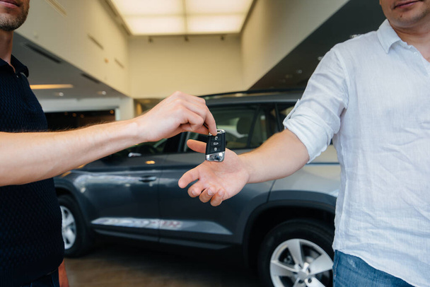The seller passes the keys to a new car to a young family. Buying a new car - Photo, image