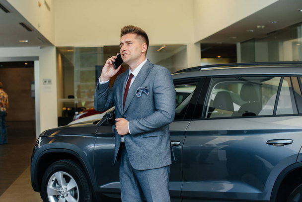A young businessman makes a phone call after buying a new car - Fotó, kép