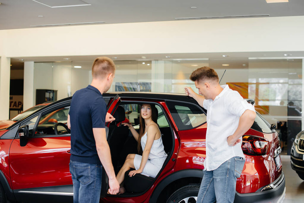 A happy young couple chooses and buys a new car at a car dealership. Buying a new car - Valokuva, kuva