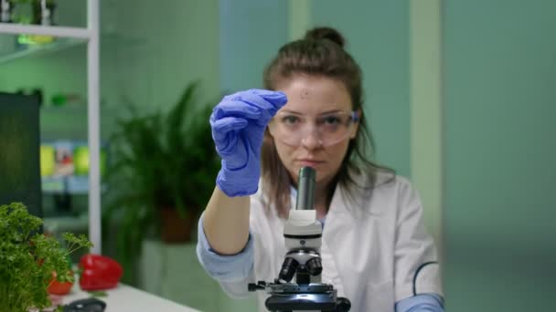 Biochemische wetenschapper die groene vloeibare steekproef met behulp van microscoop analyseert - Video