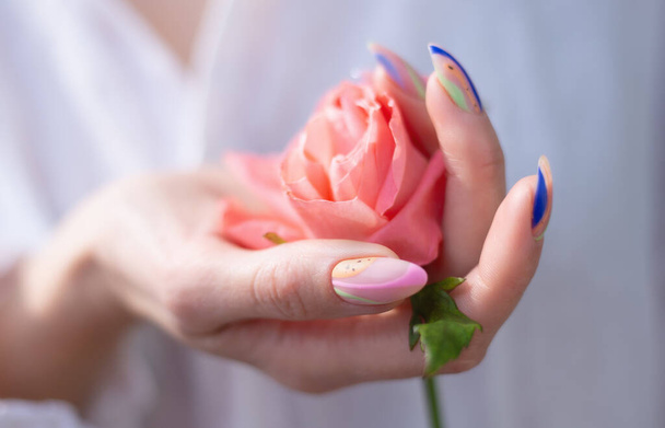 La mano de la mujer con manicura sostiene una rosa - Foto, Imagen
