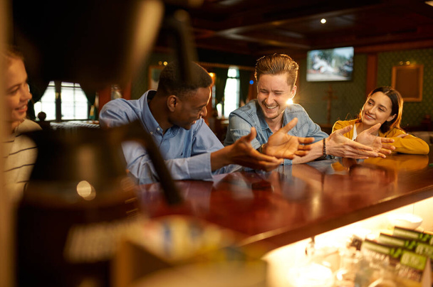 Sorrindo amigos lazeres no balcão no bar. Grupo de pessoas relaxar no pub, estilo de vida nocturno, amizade, celebração do evento - Foto, Imagem