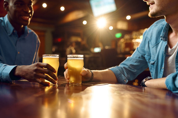 Deux amis boivent de la bière fraîche au bar. Les gens se détendent dans le pub, mode de vie nocturne, amitié, célébration de l'événement, loisirs des hommes dans le restaurant - Photo, image