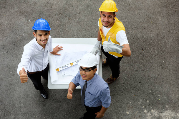Top view ázsiai mosolygós Mérnök csapat hüvelykujj fel gesztus a kamera másolás helyet szöveg. Sikeres mérnöki férfiak csoport teljes Constuction helyszíni koncepció. - Fotó, kép