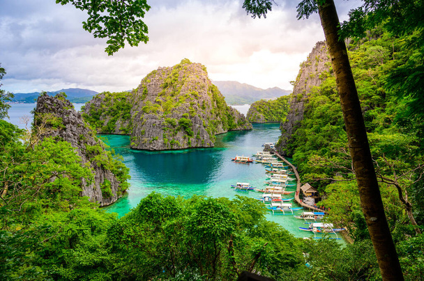 Blue crystal water in paradise Bay with boats on the wooden pier at Kayangan Lake in Coron island, Palawan, Philippines. - Foto, imagen