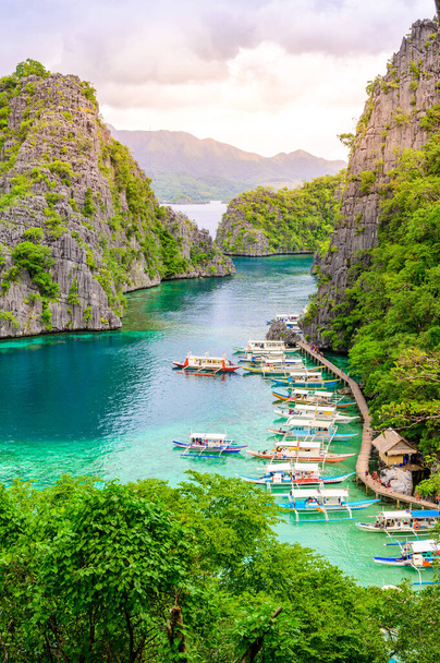 Blue crystal water in paradise Bay with boats on the wooden pier at Kayangan Lake in Coron island, Palawan, Philippines. - Foto, imagen