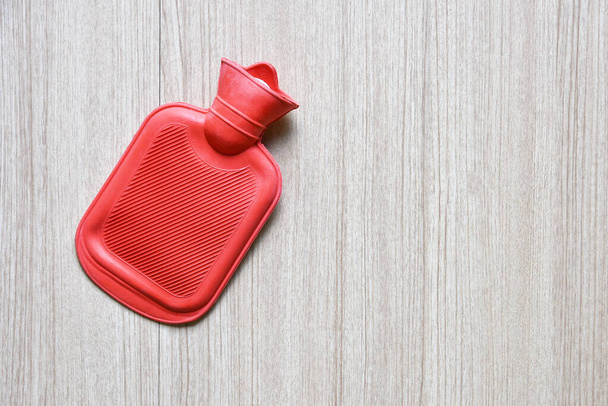 Bolsa de botella de agua caliente roja de goma sobre mesa de madera - Foto, Imagen