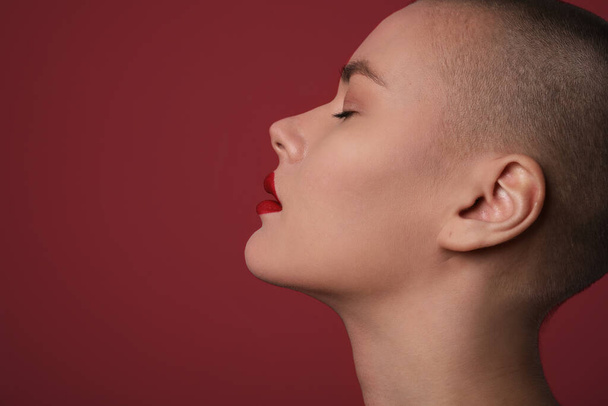 Side portrait of a beautiful bald woman over red background. - 写真・画像