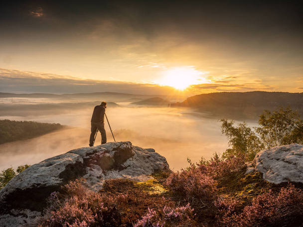 Ландшафтний фотограф у дії, фотографуючи. Силуетний чоловік фотографує проти туманного пейзажу та ранкового неба. осінній барвистий захід сонця
 - Фото, зображення