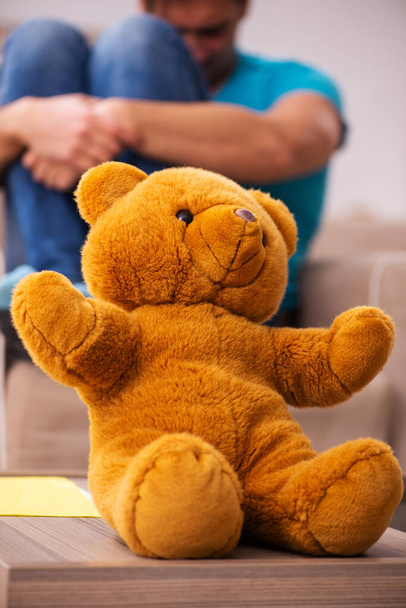 Young man sitting with bear toy at home - Photo, Image