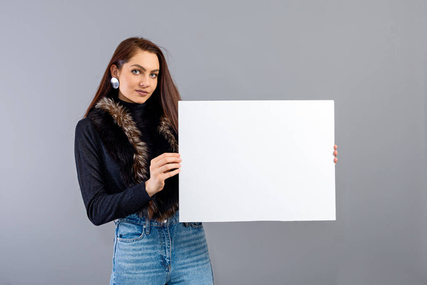 elegant young teenager woman showing blank signboard with copy space, isolated on gray - Fotoğraf, Görsel