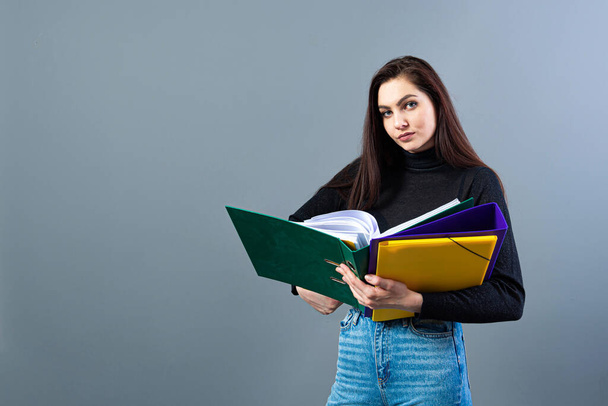 fashionable woman holding a colorfuls folders with documents, isolated on dark background - Photo, Image