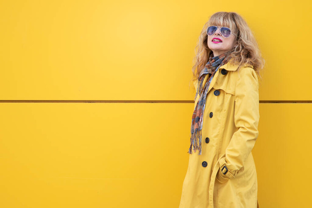 mulher adulta atraente na parede amarela na rua ao ar livre - Foto, Imagem