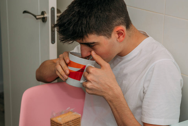 young man having breakfast in the kitchen at home - Foto, afbeelding
