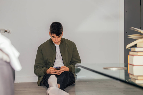 tiener jongen thuis met mobiele telefoon op de vloer - Foto, afbeelding