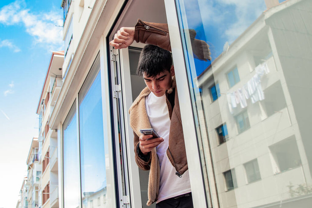 молодой человек на террасе дома с мобильным телефоном - Фото, изображение