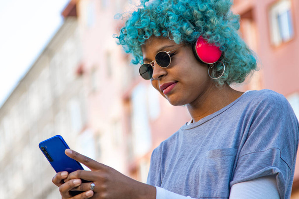 afro american girl smiling with headphones and mobile phone in the city - Foto, afbeelding
