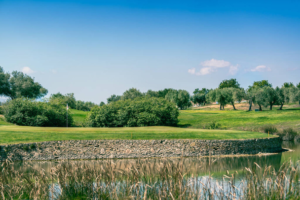 Terrain de golf vert avec risque d'eau et mur de pierre - Photo, image