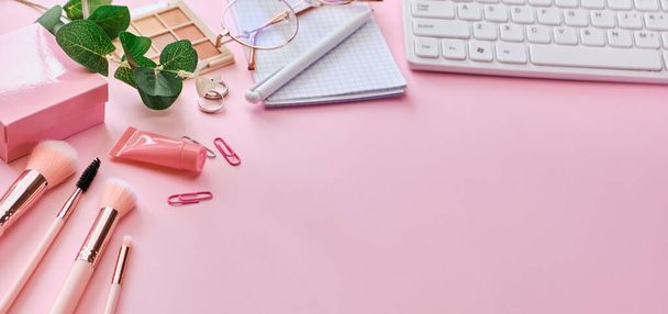 Banner Flat lay, vista superior rosa mesa de oficina moderna. Espacio de trabajo con teclado, bloc de notas, gafas, bolígrafos, accesorios de belleza sobre fondo rosa. Trabajo en línea, compras, cursos y concepto de formación - Foto, imagen