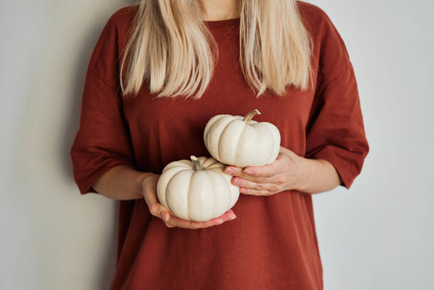Pumpkins in the hands of a girl in a red T-shirt. Natural fresh organic vegetables. White pumpkin close-up. Raw food diet healthy. Pumpkin Day, Thanksgiving and Halloween. Poster, banner - Fotografie, Obrázek