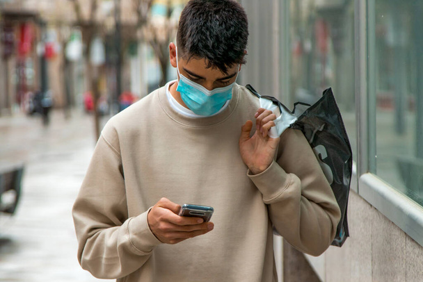 young teenager boy with mask and mobile phone shopping - Photo, Image