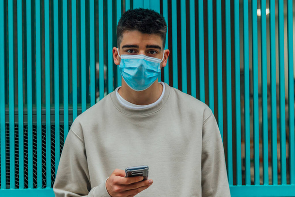 male adolescent with mask and mobile phone - Photo, Image