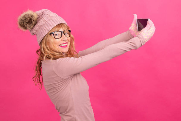 atractiva mujer adulta con teléfono móvil aislado con ropa de abrigo - Foto, imagen