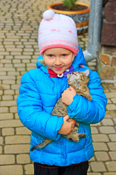 Girl with kitten in arms. Children love for animals. Favorite pet. Child with gray kitten in her arms. Friendship kids. Baby with cat. Portrait of child with little cat. Little friends - Foto, immagini