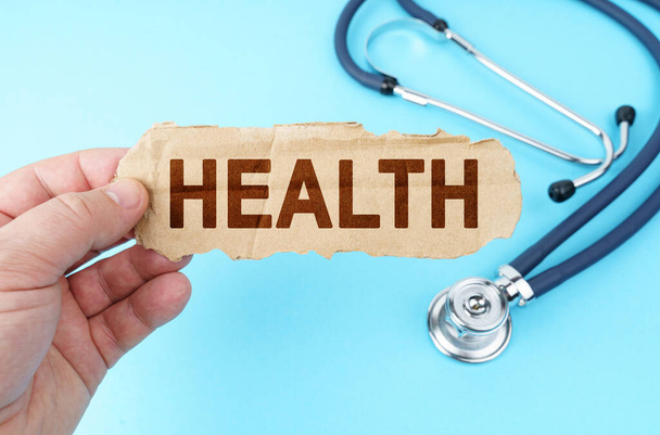 Medicine and health concept. On a blue background, a man holds a cardboard box with the inscription - HEALTH - Zdjęcie, obraz
