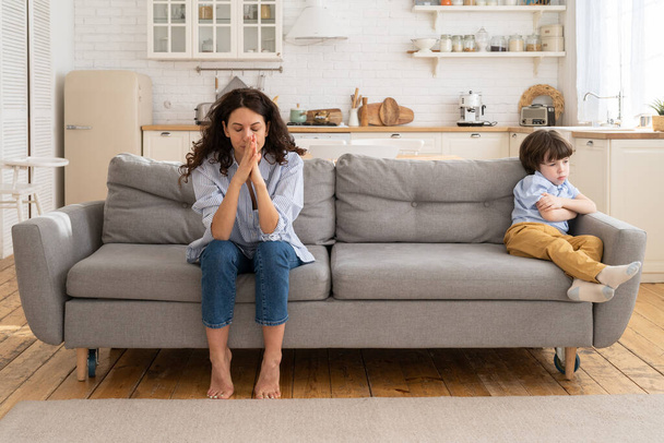 Sértett anya és fia ülnek a kanapén a nappaliban elkerülve a beszélgetést nézik egymást veszekedés után - Fotó, kép