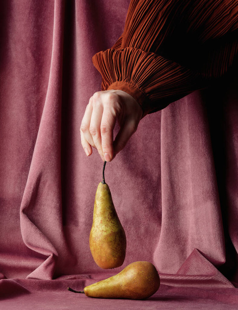 Female hold pear on burgundy color fabric background  - Fotografie, Obrázek