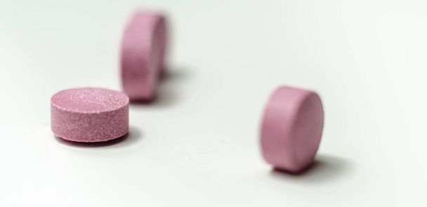 pilules pourpres dispersées sur un fond blanc, compléments alimentaires qui comprend des baies d'açai, médicaments - Photo, image