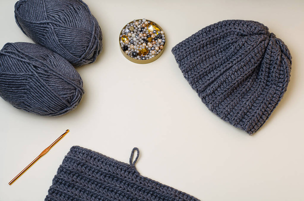 Knitted gray hat, pebbles for hand-made, for handmade. Gray beads and pebbles.Do it yourself.Crafts from threads for knitting.Acrylic thread.Pantone colors2021.Gray yellow - Foto, Imagem