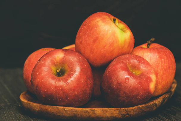 Red apples in a wooden plate on dark background. apple red wooden fruit sweet healthy food - Fotoğraf, Görsel