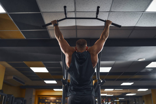 Man in gym doing exercises on crossbar in gym - 写真・画像