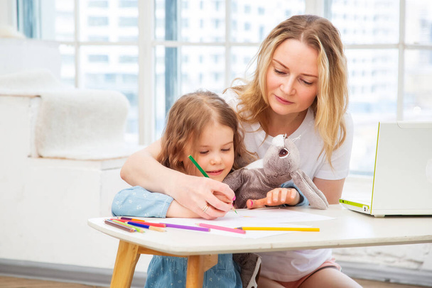 gelukkig blank mam met dochter zitten op de woonkamer vloer en samen tekenen, besteden tijd met hun familie doen kunst - Foto, afbeelding