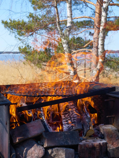 Fire in a rusty vintage grill outdoor on the beach of the sea. - Photo, Image