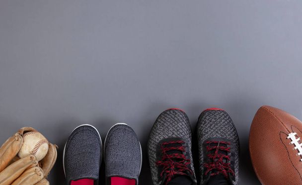 Vatertagskonzept mit Erwachsenen- und Kinderschuhen und Sportballausrüstung auf grauem Hintergrund im flachen Lageformat - Foto, Bild