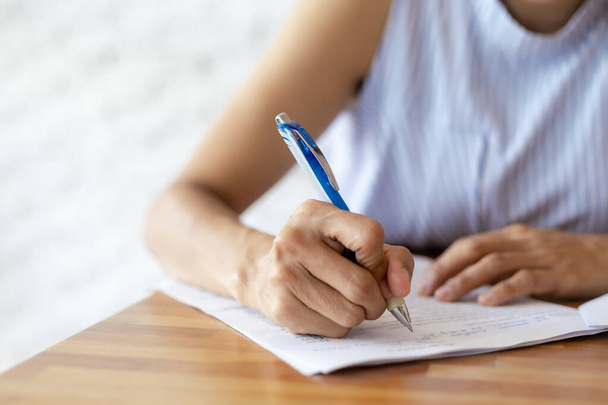 ビジネスの女性の手を閉じるには、ペンの文書紙を使用します。白いシートに青いペンで書く女性の手を閉じます。女性は紙に情報を書きます. - 写真・画像