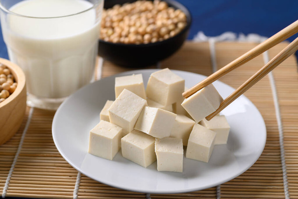 Viipaloitu tofu valkoisella lautasella syömäpuikoilla, Terveellinen vegaaninen ruoka - Valokuva, kuva
